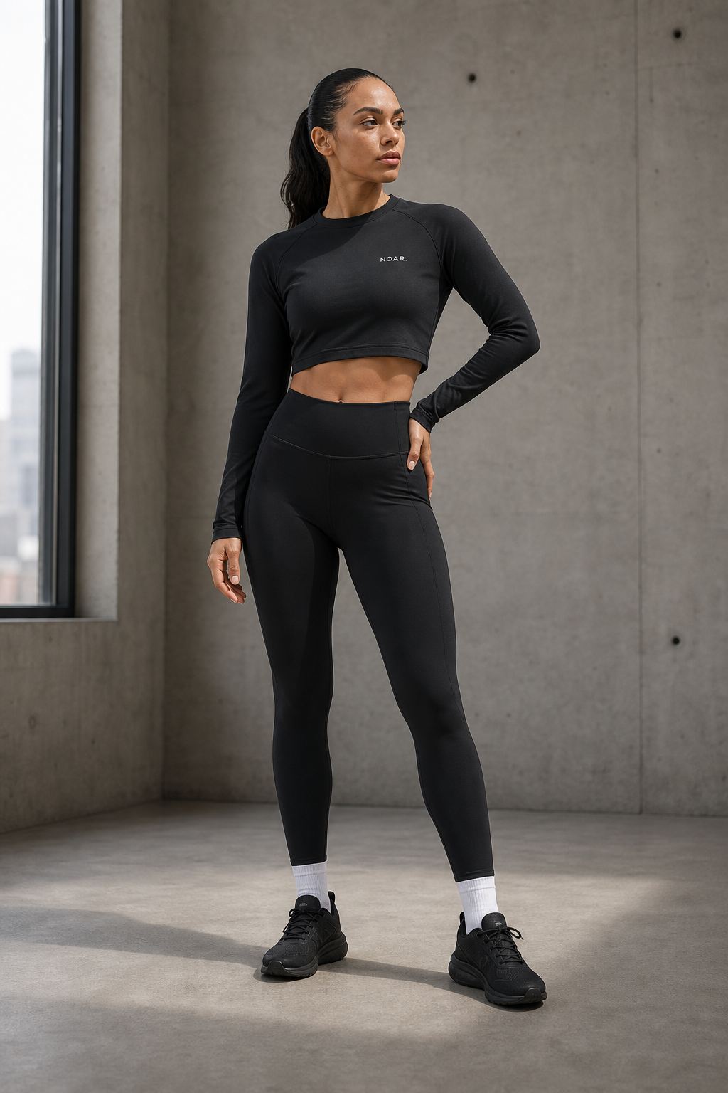 Female model wearing black NOAR leggings and cropped training top